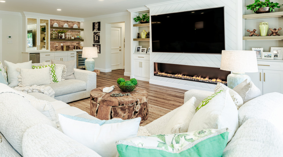Réalisation d'une grande salle de séjour champêtre ouverte avec un mur blanc, un sol en vinyl, un manteau de cheminée en lambris de bois, un téléviseur encastré et un sol marron.