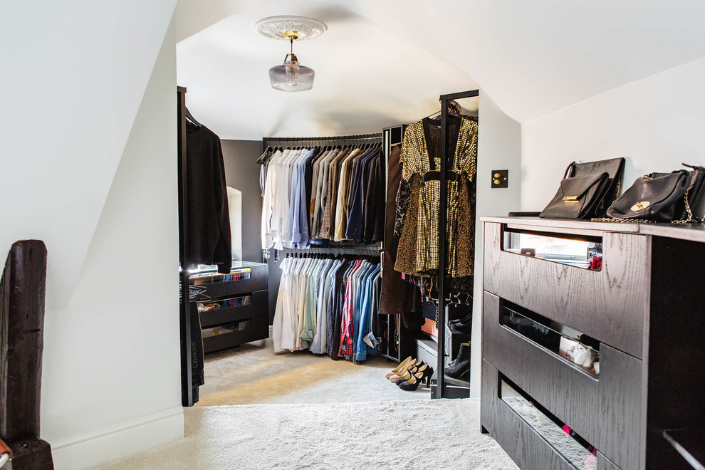 Design ideas for a mid-sized scandinavian gender-neutral walk-in wardrobe in Stockholm with flat-panel cabinets, dark wood cabinets and carpet.