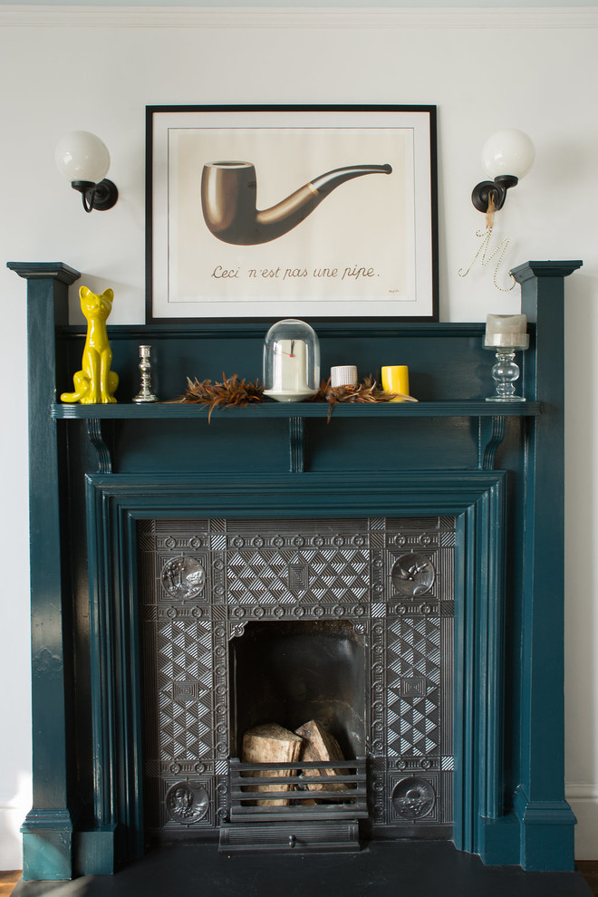 Traditional living room with white walls, dark hardwood flooring, a wood burning stove and a metal fireplace surround.