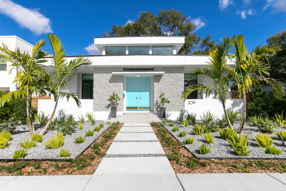 Photo of a large midcentury one-storey white house exterior in Tampa with a flat roof.