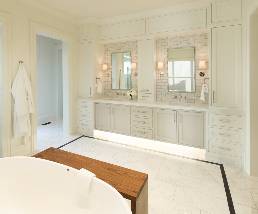 This is an example of a traditional bathroom in Salt Lake City with recessed-panel cabinets, white cabinets, a freestanding tub, white tile, subway tile, white walls, an undermount sink and white floor.