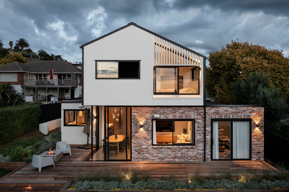 Mittelgroßes, Zweistöckiges Modernes Einfamilienhaus mit Backsteinfassade, weißer Fassadenfarbe, Satteldach, Blechdach, schwarzem Dach und Wandpaneelen in Auckland