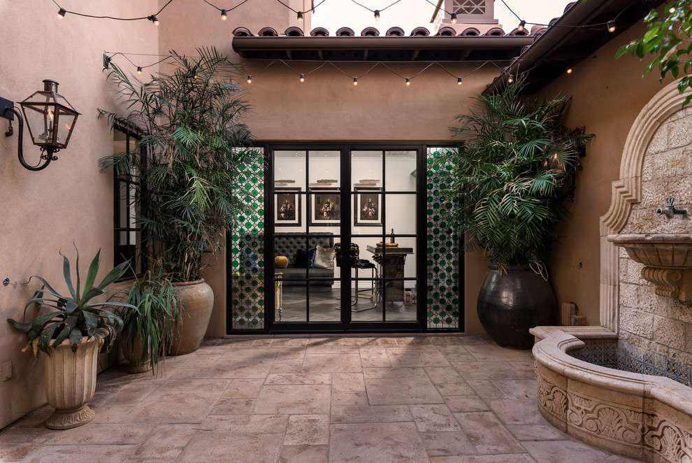 This is an example of an expansive mediterranean courtyard patio in Phoenix with a water feature, natural stone pavers and no cover.