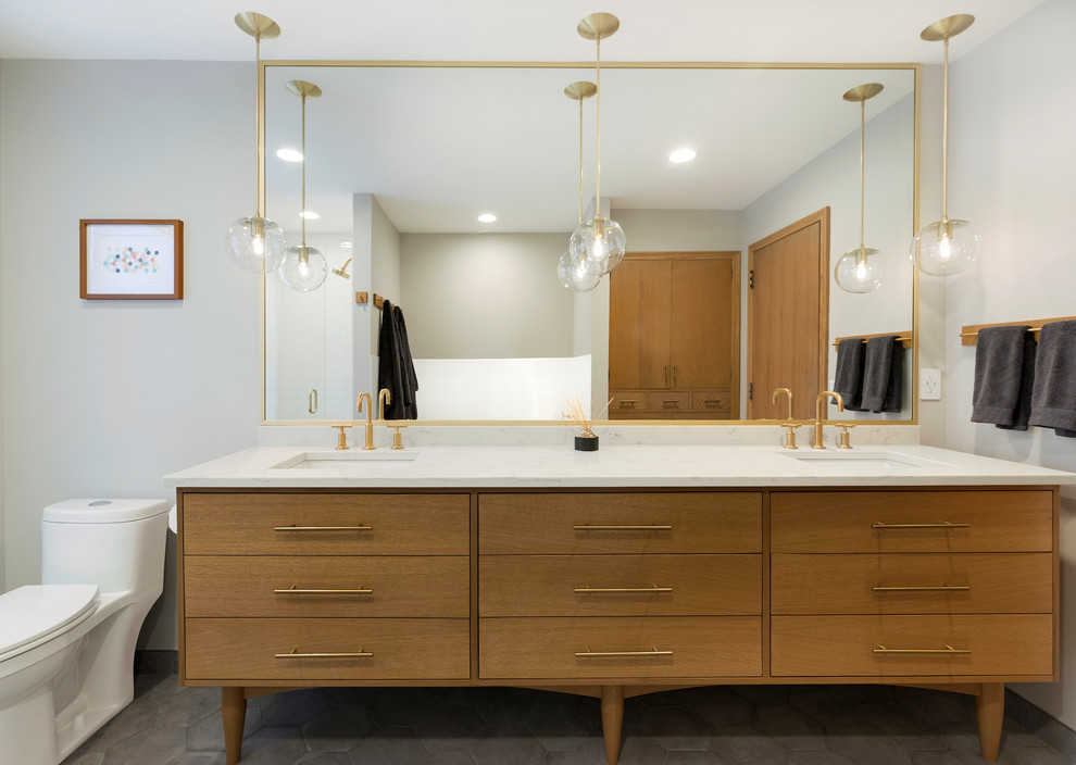 Inspiration for a mid-sized midcentury master bathroom in Minneapolis with medium wood cabinets, an alcove tub, an alcove shower, a one-piece toilet, white tile, subway tile, grey walls, porcelain floors, an undermount sink, engineered quartz benchtops, grey floor, a hinged shower door and flat-panel cabinets.