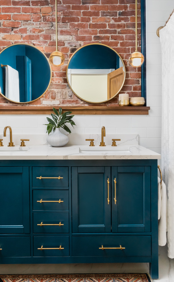 На фото: ванная комната в стиле неоклассика (современная классика) с синими фасадами, душем над ванной, синими стенами, полом из керамогранита, мраморной столешницей, белым полом, белой столешницей, тумбой под две раковины, напольной тумбой и кирпичными стенами с