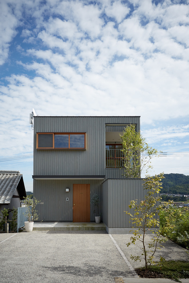 Mid-sized asian three-storey grey house exterior in Other with wood siding, a shed roof and a metal roof.