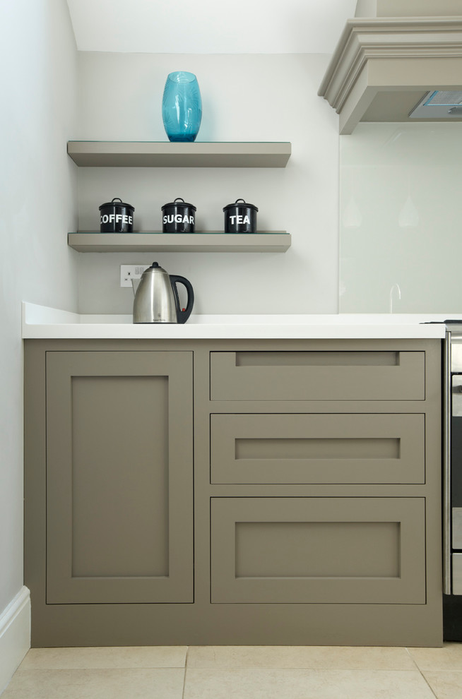Mid-sized transitional galley kitchen in London with an undermount sink, shaker cabinets, grey cabinets, solid surface benchtops, grey splashback, glass sheet splashback, stainless steel appliances, ceramic floors and with island.