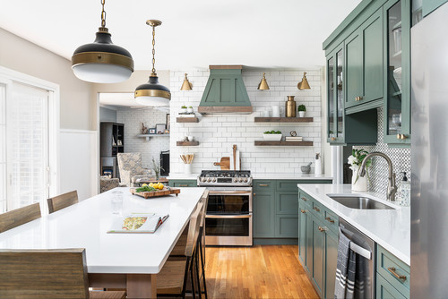 Modern galley kitchen with sage-green shaker RTA cabinets, white quartz counters, subway tile backsplash, open wood shelves, and brass lighting.