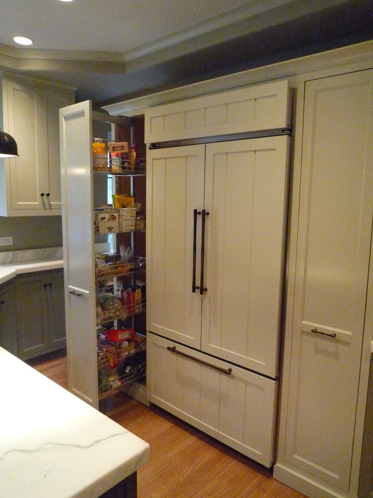 Enclosed kitchen - transitional medium tone wood floor enclosed kitchen idea with shaker cabinets, white cabinets, marble countertops, white backsplash, stone slab backsplash, paneled appliances and an island