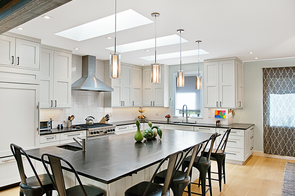 Design ideas for a transitional l-shaped kitchen in Denver with an undermount sink, shaker cabinets, grey cabinets, white splashback, panelled appliances, light hardwood floors, with island, beige floor and blue benchtop.