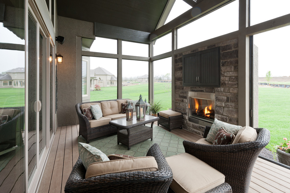 This is an example of a mid-sized transitional backyard deck in Kansas City with a fire feature and a roof extension.