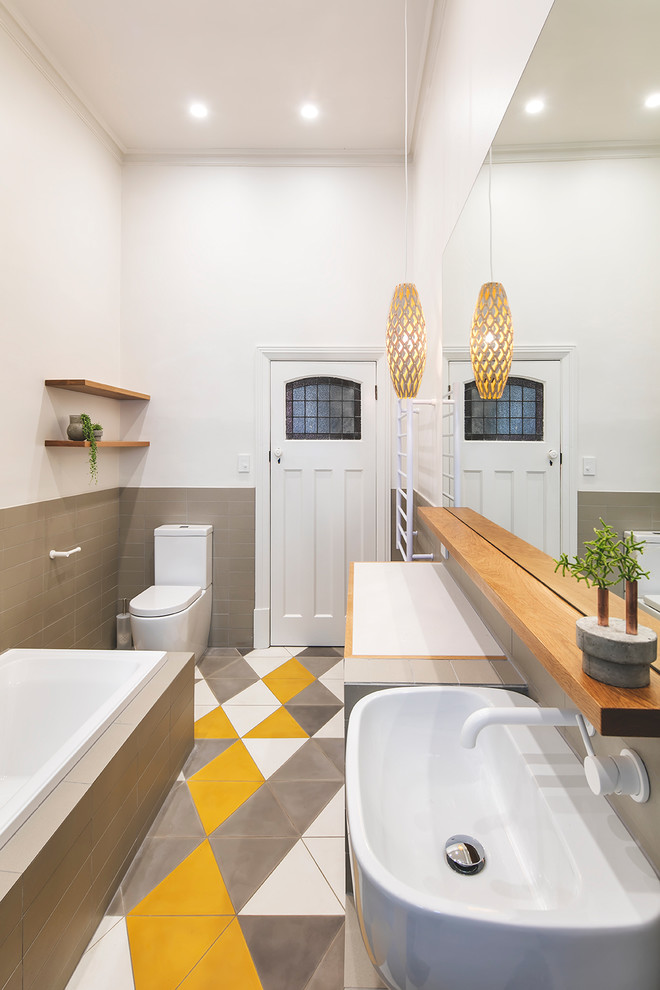 Inspiration for a contemporary master bathroom in Adelaide with medium wood cabinets, a drop-in tub, an alcove shower, ceramic tile, white walls, porcelain floors, a wall-mount sink and multi-coloured tile.