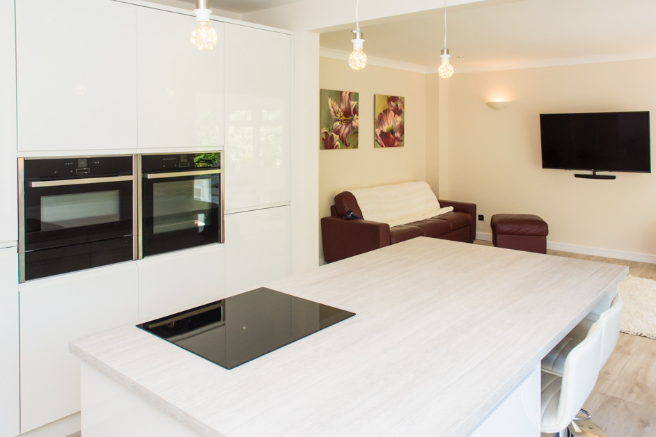 Mid-sized modern kitchen in Sussex with a drop-in sink, beige cabinets, laminate benchtops, beige splashback, black appliances, plywood floors, with island, beige floor and beige benchtop.