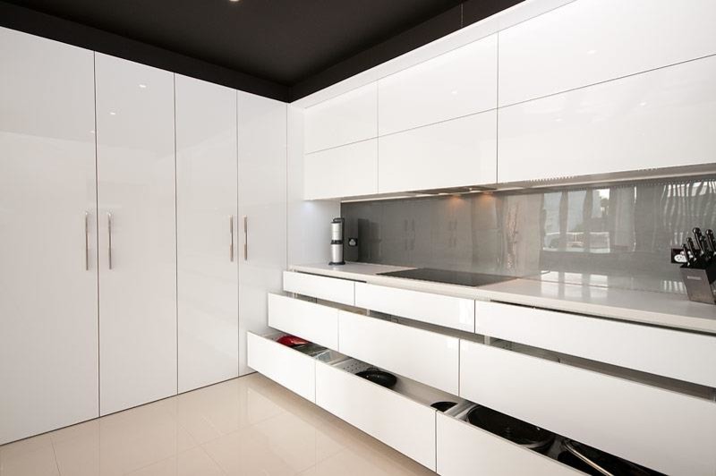 Photo of a large modern single-wall separate kitchen in Gold Coast - Tweed with an undermount sink, flat-panel cabinets, white cabinets, quartz benchtops, grey splashback, glass sheet splashback, stainless steel appliances, ceramic floors and with island.