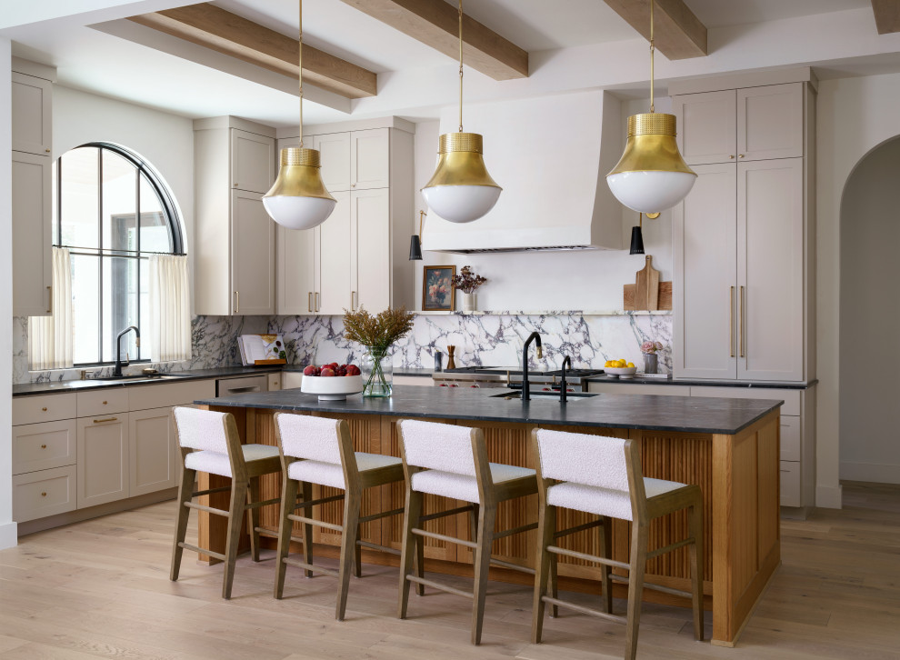 Inspiration for a transitional l-shaped light wood floor, beige floor and exposed beam kitchen remodel in Austin with an undermount sink, shaker cabinets, beige cabinets, gray backsplash, stainless steel appliances, an island and black countertops