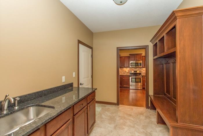 This is an example of a traditional laundry room in Other with open cabinets, medium wood cabinets, granite benchtops, ceramic floors and a side-by-side washer and dryer.