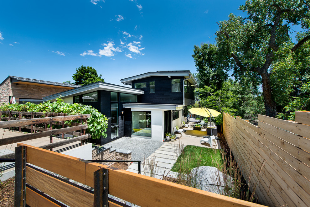 This is an example of a mid-sized contemporary three-storey black house exterior in Denver with mixed siding, a flat roof and a mixed roof.