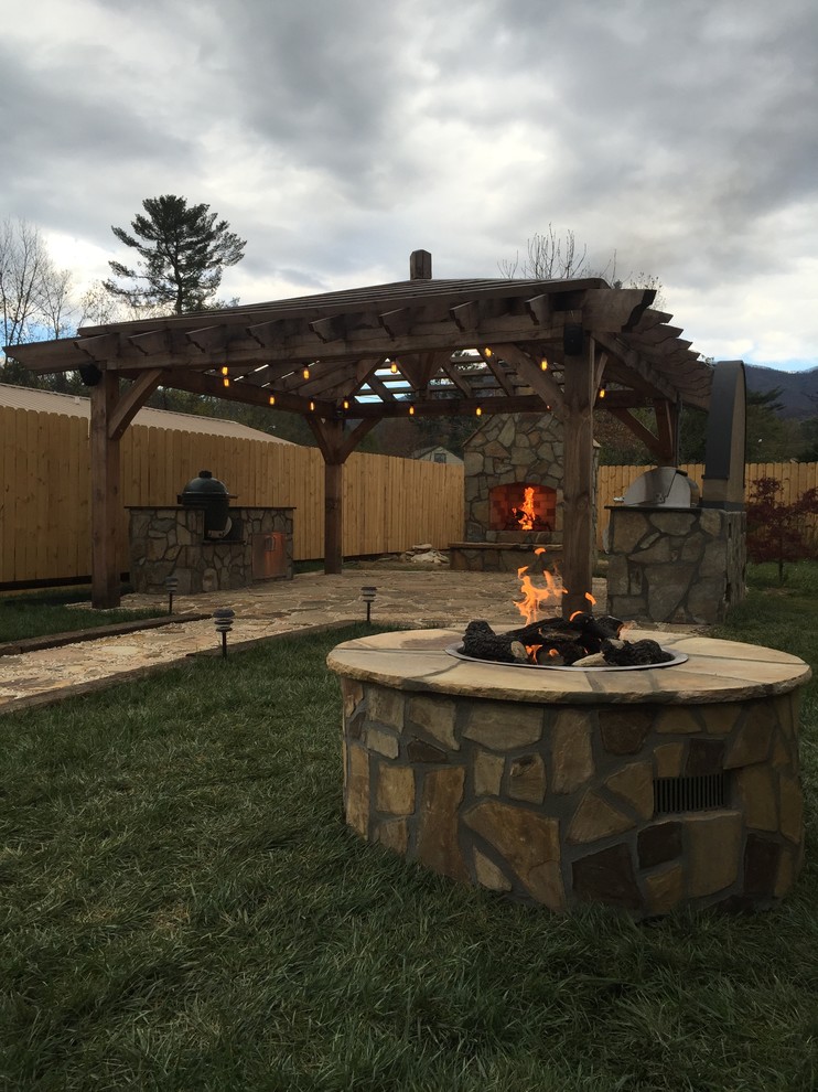 Example of a large transitional backyard stone patio design with a fire pit and a pergola