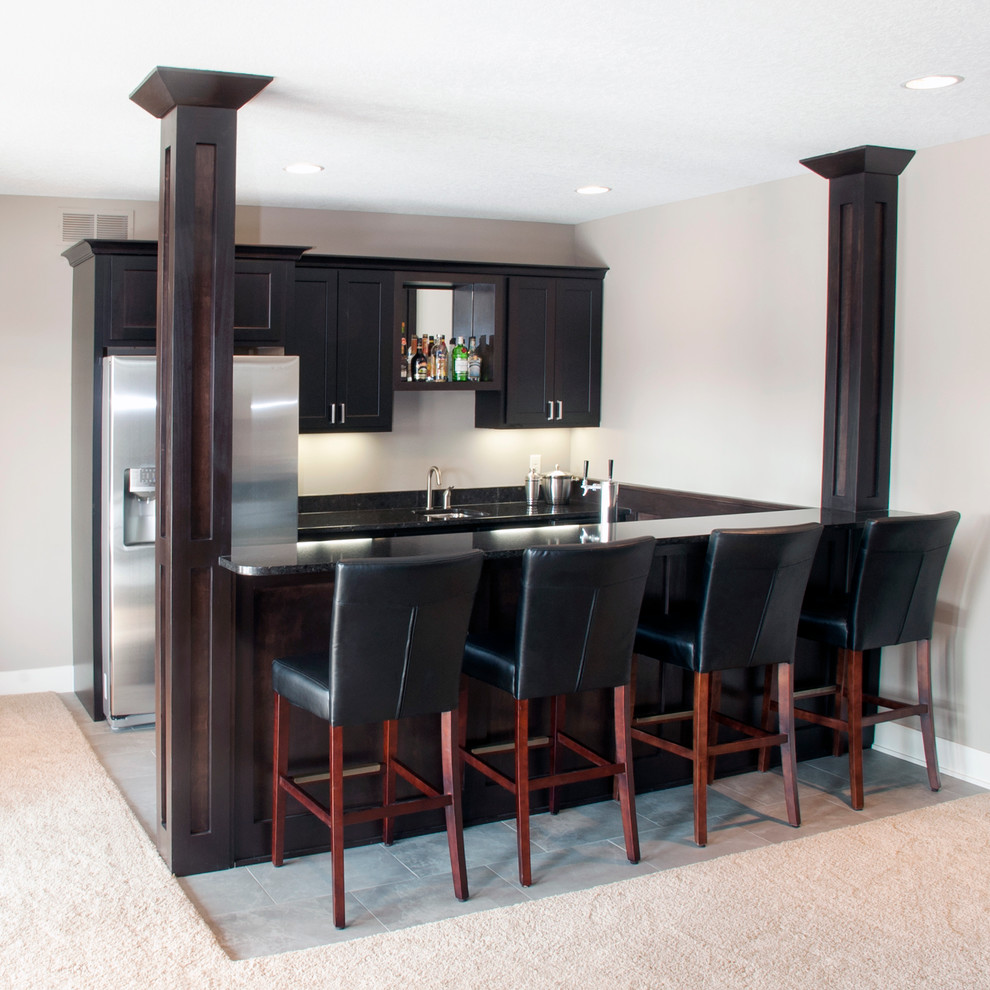 Photo of a contemporary single-wall seated home bar in New York with shaker cabinets, dark wood cabinets, granite benchtops and slate floors.