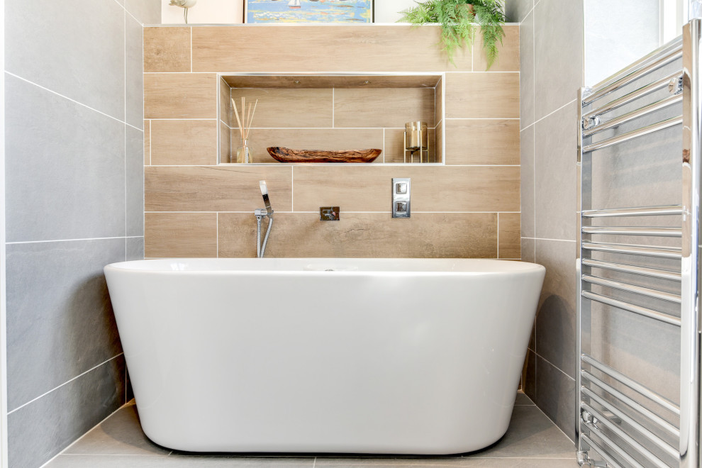 Стильный дизайн: большая главная, серо-белая ванная комната: освещение в стиле модернизм с плоскими фасадами, серыми фасадами, отдельно стоящей ванной, открытым душем, унитазом-моноблоком, серой плиткой, керамической плиткой, серыми стенами, полом из керамической плитки, накладной раковиной, стеклянной столешницей, серым полом, открытым душем, белой столешницей, тумбой под одну раковину и подвесной тумбой - последний тренд
