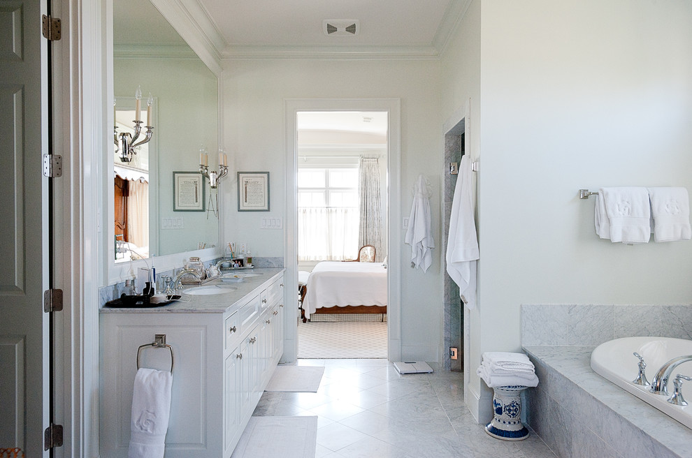 Photo of a large traditional master bathroom in Dallas with raised-panel cabinets, white cabinets, a drop-in tub, a one-piece toilet, gray tile, white tile, white walls, marble floors, an undermount sink, marble benchtops, marble and grey benchtops.