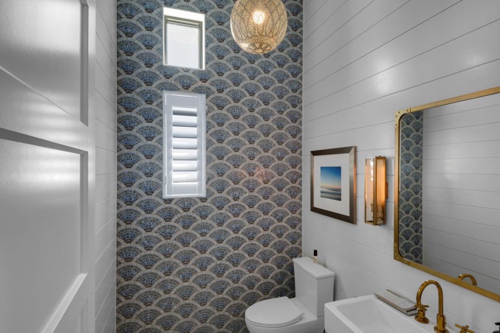 Пример оригинального дизайна: маленький туалет в морском стиле с унитазом-моноблоком, синими стенами, раковиной с несколькими смесителями, подвесной тумбой и обоями на стенах для на участке и в саду