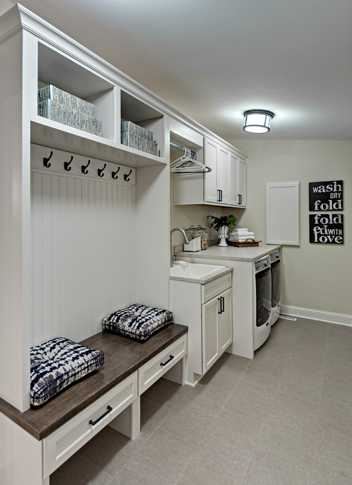 Small country single-wall utility room in Minneapolis with a drop-in sink, white cabinets, laminate benchtops, beige walls, porcelain floors, a side-by-side washer and dryer and recessed-panel cabinets.