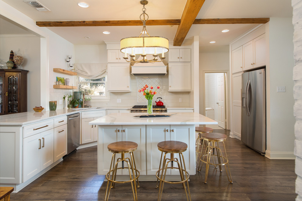 This is an example of a mid-sized country u-shaped kitchen in New Orleans with shaker cabinets, white cabinets, white splashback, stainless steel appliances, dark hardwood floors, with island and brown floor.