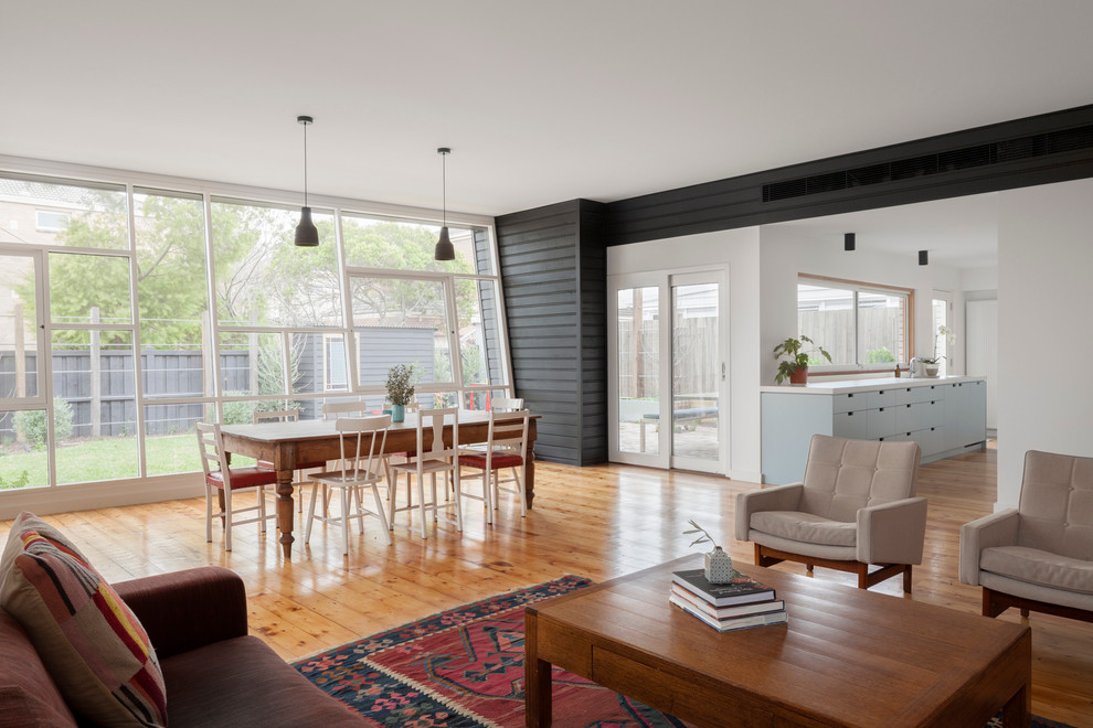 This is an example of a mid-sized contemporary open concept living room in Melbourne with black walls and light hardwood floors.