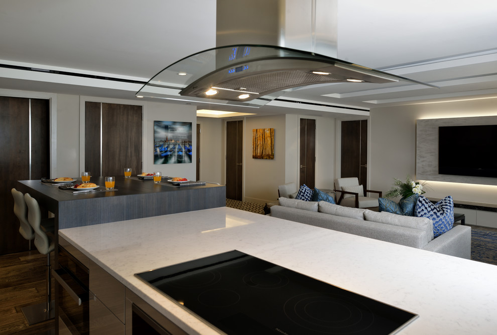 Inspiration for a small contemporary galley open plan kitchen in Houston with an undermount sink, flat-panel cabinets, white cabinets, quartz benchtops, white splashback, glass sheet splashback, panelled appliances, medium hardwood floors and with island.
