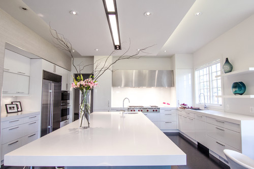 Bright modern kitchen with white flat-panel cabinets, oversized island, stainless appliances, and a linear ceiling light