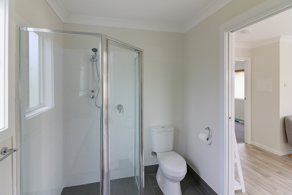 Photo of a small contemporary bathroom in Central Coast with an alcove shower, a one-piece toilet, gray tile, ceramic tile, white walls and ceramic floors.