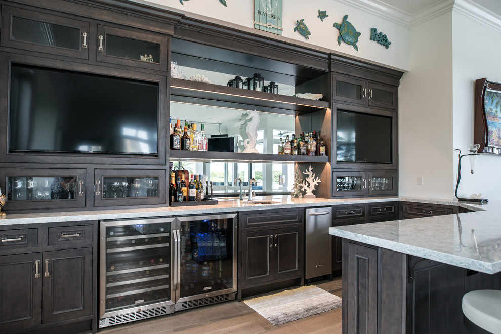 Inspiration for a large transitional u-shaped seated home bar in Miami with an undermount sink, recessed-panel cabinets, dark wood cabinets, granite benchtops and porcelain floors.