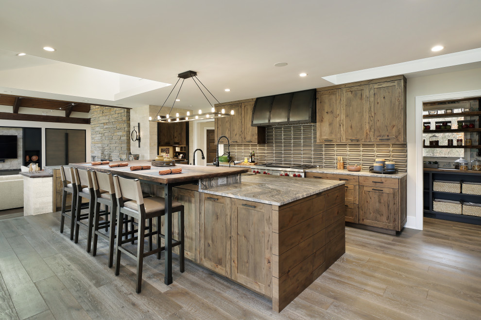 Country galley kitchen in Chicago with shaker cabinets, medium wood cabinets, grey splashback, stainless steel appliances, medium hardwood floors, with island, brown floor and grey benchtop.