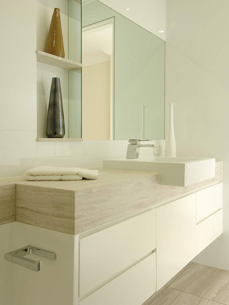 Стильный дизайн: главная ванная комната среднего размера в стиле модернизм с плоскими фасадами, белыми фасадами, накладной ванной, душем в нише, унитазом-моноблоком, белой плиткой, керамической плиткой, белыми стенами, полом из известняка, настольной раковиной, столешницей из известняка, бежевым полом, открытым душем, бежевой столешницей, нишей, тумбой под одну раковину, подвесной тумбой, многоуровневым потолком и панелями на стенах - последний тренд