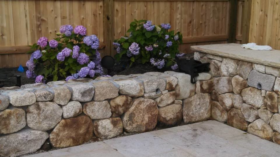 Photo of a mid-sized transitional full sun backyard stone landscaping in Boston for spring.