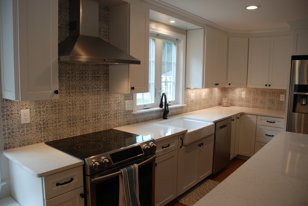 This is an example of a mid-sized traditional u-shaped eat-in kitchen in Boston with a farmhouse sink, shaker cabinets, white cabinets, marble benchtops, multi-coloured splashback, slate splashback, stainless steel appliances, light hardwood floors, with island, brown floor and white benchtop.