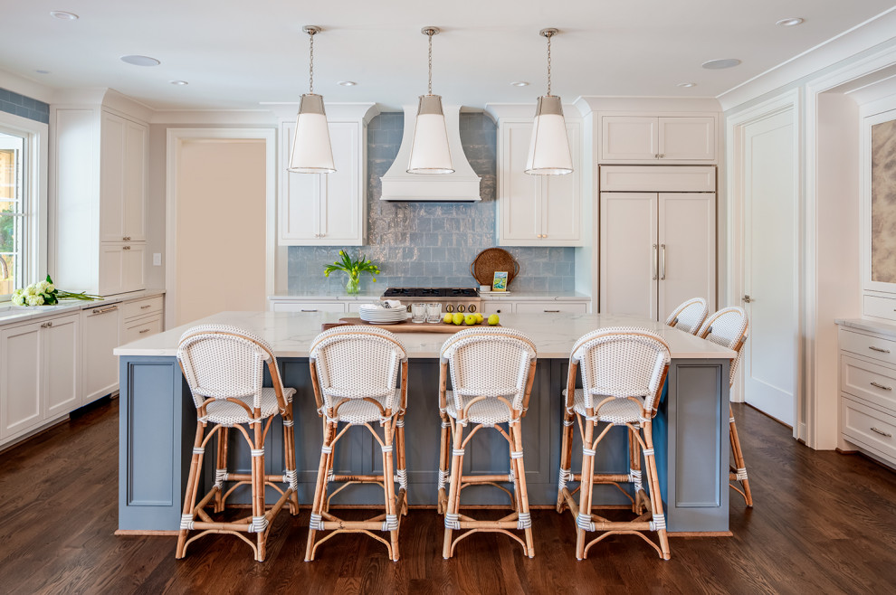 Example of a large transitional l-shaped medium tone wood floor and brown floor eat-in kitchen design with an integrated sink, shaker cabinets, white cabinets, quartzite countertops, blue backsplash, ceramic backsplash, paneled appliances, an island and white countertops