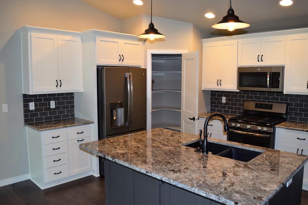 Example of a mountain style kitchen design with white cabinets, stainless steel appliances and an island