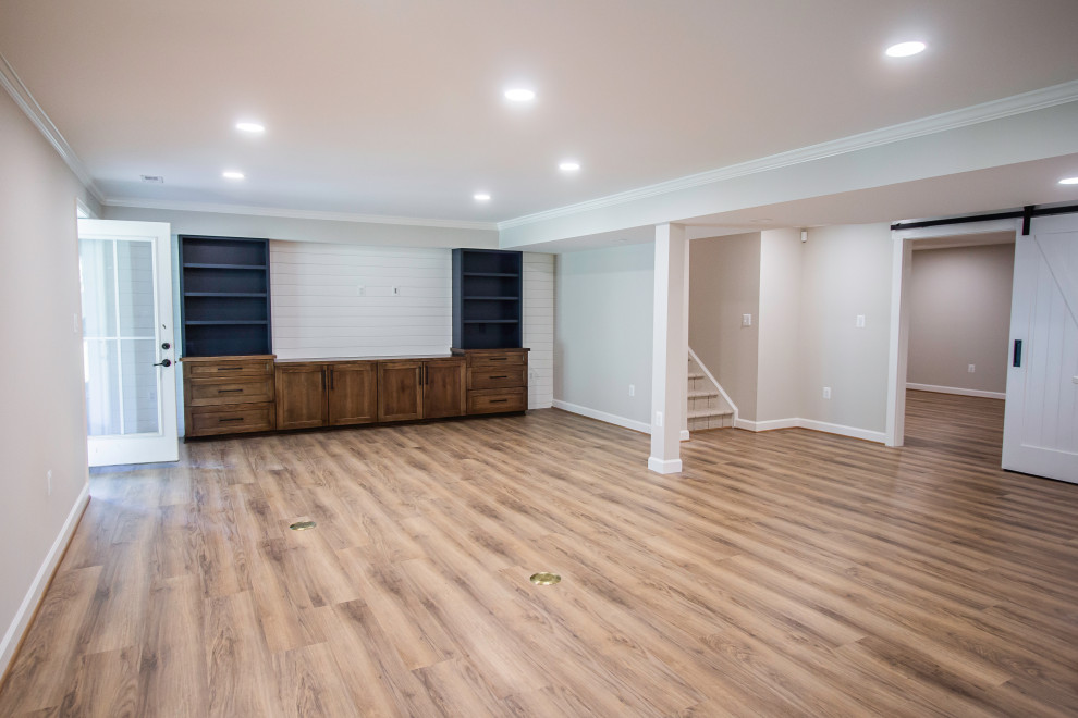 Basement - huge transitional walk-out vinyl floor and brown floor basement idea in DC Metro with a bar and white walls