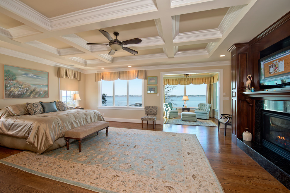 Photo of an expansive traditional master bedroom in Other with beige walls, a standard fireplace, a tile fireplace surround, brown floor and dark hardwood floors.