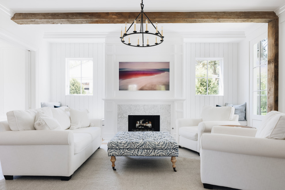 South Coast Farmhouse - Art-like design features delineate spaces in this light and bright living area, including a simple white marble fireplace surround, a tv that doubles as art work, windows framing nature outside in lieu of paintings, panel molding that gives texture to the walls while accenting the built-in seating, as well as a dramatic focal light fixture. Reclaimed Wisconsin barn beams delineating spaces for the kitchen and living areas