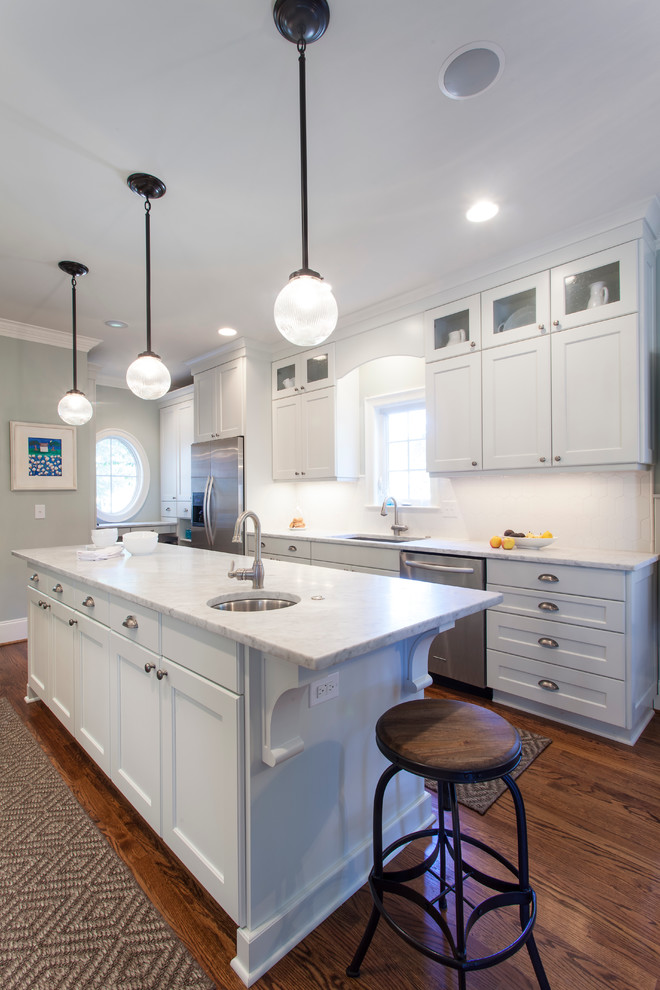 Mid-sized transitional u-shaped medium tone wood floor and brown floor eat-in kitchen photo in Charlotte with an undermount sink, shaker cabinets, white cabinets, quartzite countertops, white backsplash, stainless steel appliances, an island and porcelain backsplash