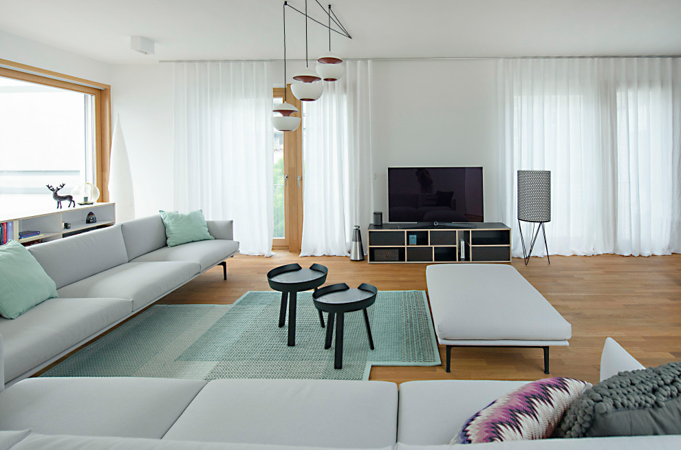 Cette image montre une grande salle de séjour design ouverte avec un sol en bois brun et un sol marron.