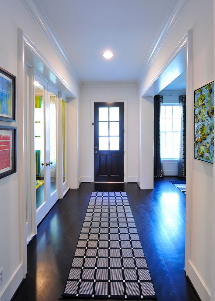This is an example of a small modern hallway in Houston with white walls and dark hardwood floors.