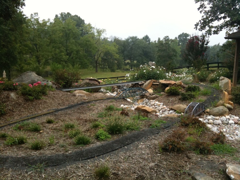 Design ideas for a large rustic partial sun backyard stone formal garden for summer.