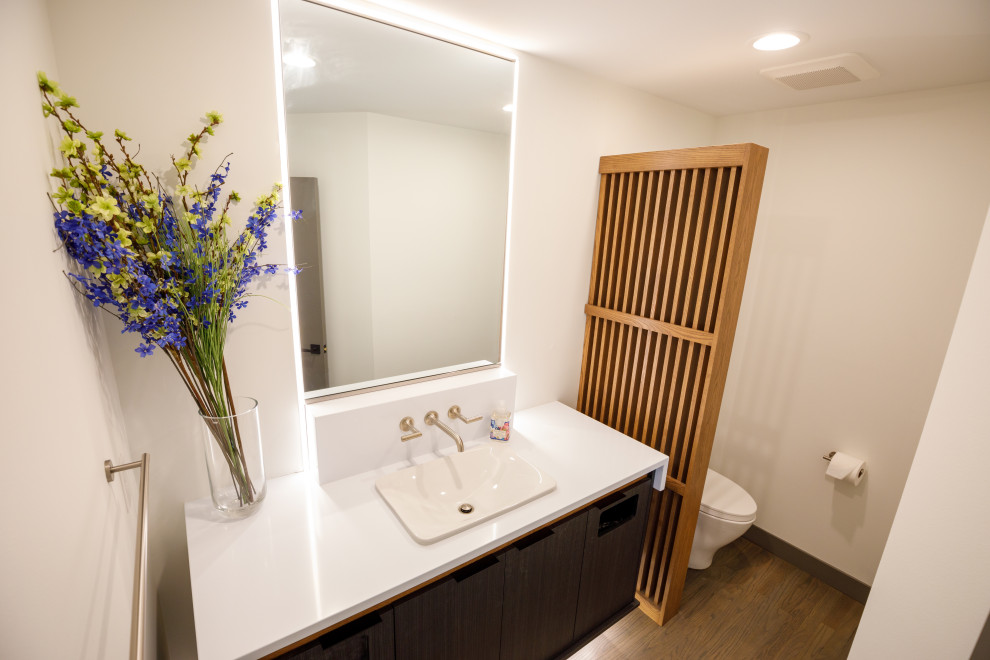 Design ideas for a small contemporary powder room in Minneapolis with flat-panel cabinets, dark wood cabinets, a one-piece toilet, white walls, wood-look tile, a drop-in sink, engineered quartz benchtops, brown floor, white benchtops and a floating vanity.