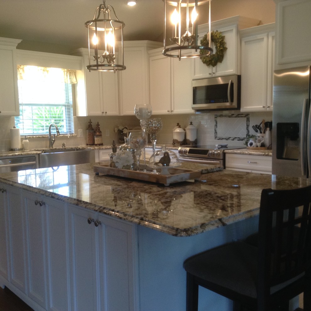 Mid-sized transitional l-shaped medium tone wood floor and brown floor eat-in kitchen photo in Orlando with a farmhouse sink, recessed-panel cabinets, white cabinets, granite countertops, white backsplash, subway tile backsplash, stainless steel appliances and an island