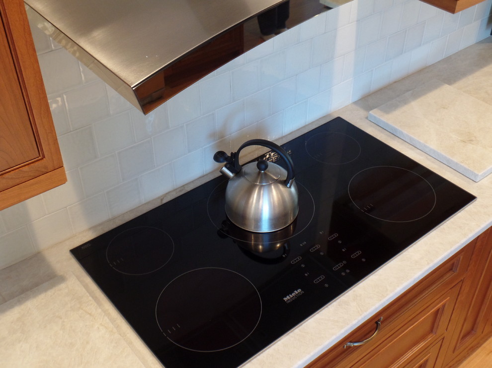 Large transitional l-shaped light wood floor open concept kitchen photo with a single-bowl sink, beaded inset cabinets, medium tone wood cabinets, quartzite countertops, white backsplash, ceramic backsplash, stainless steel appliances and no island