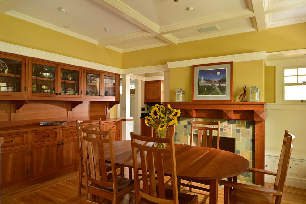 Photo of an arts and crafts dining room in San Francisco with yellow walls, medium hardwood floors, a standard fireplace and a tile fireplace surround.